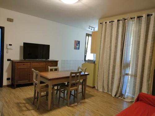 una sala da pranzo con tavolo, sedie e TV di Appartamento Nanda a Reggio Emilia