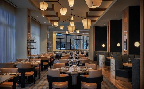 uma sala de jantar com mesas, cadeiras e luzes em Pendry Park City em Park City