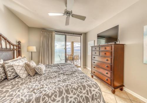 a bedroom with a bed and a dresser with a television at Bluewater in Orange Beach