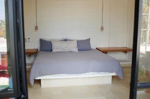 a bed with blue pillows in a room at Punta Mita Surf Lodge in Punta Mita