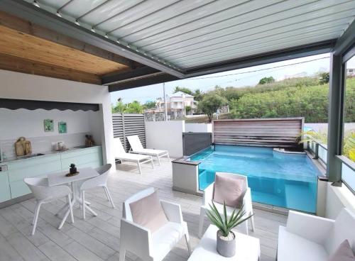 eine Terrasse mit einem Pool, Stühlen und einem Tisch in der Unterkunft Habitation I'SEO Adult Only in Sainte-Anne