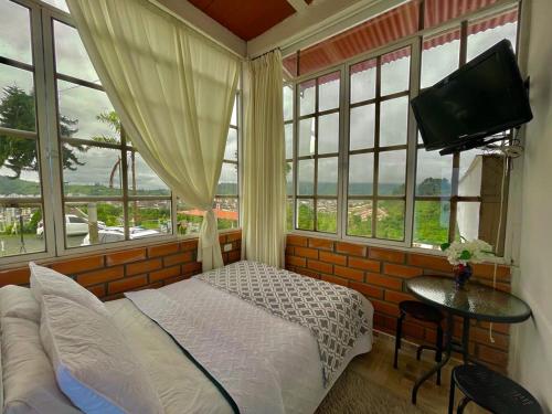 1 dormitorio con 1 cama, TV y ventanas en Mirador San Jose, en Santa Rosa de Cabal