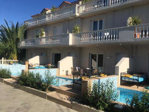 a building with a swimming pool next to a resort at Three Graces Holiday Houses Complex in Laganas