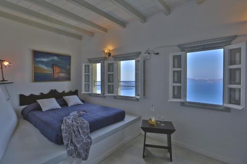 a bedroom with a blue bed and windows at Cori Rigas Suites in Fira
