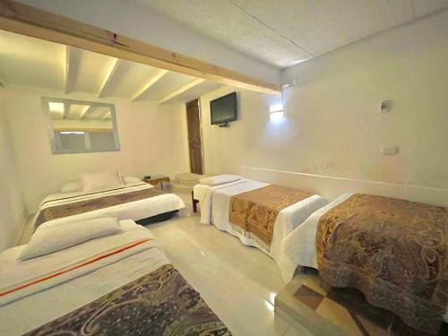 a hotel room with three beds and a tv at Mirador San Jose in Santa Rosa de Cabal