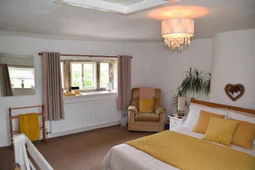 - une chambre avec un lit, une chaise et un lustre dans l'établissement Sweetbriar Cottage Bed & Breakfast and Camping, à Starbotton