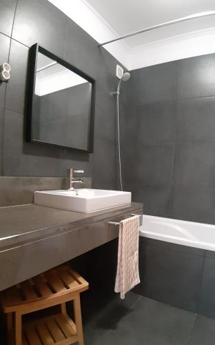 a bathroom with a sink and a mirror and a tub at Amateur Runners in Água de Alto