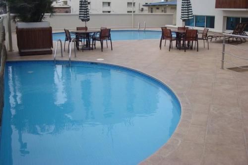 una gran piscina azul con sillas y mesas. en Ecusuites Salinas Resort Aquamira Balcony, en Salinas