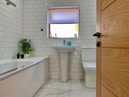 uma casa de banho com um lavatório, uma banheira e um WC. em Business friendly & Spacious 2BR home - Perfectly located for working in Swansea em Swansea
