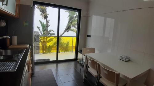 a kitchen with a table and a large window at Amateur Runners in Água de Alto