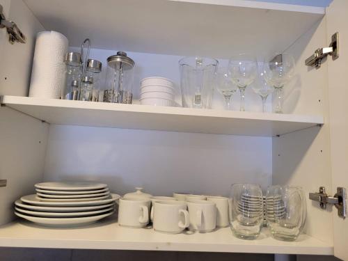 un estante lleno de vasos, platos y tazas en Departamento Céntrico muy cómodo, en San Juan