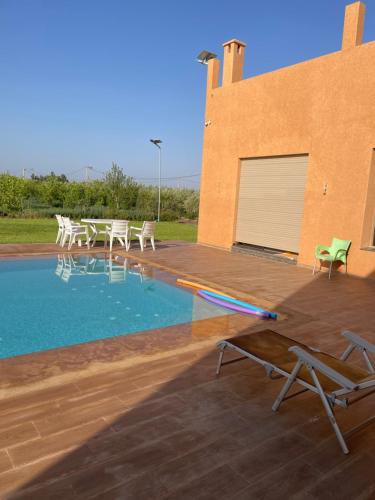 uma piscina com cadeiras e um edifício em Villa atlas farm strictement pour les familles em Marrakech