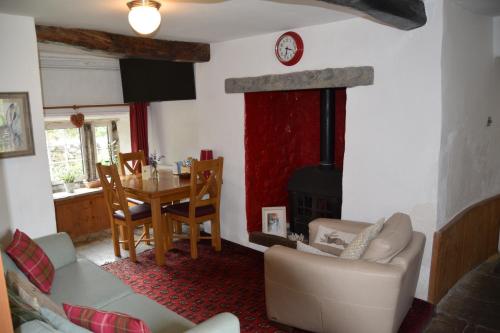 - un salon avec un canapé, une table et une cheminée dans l'établissement Sweetbriar Cottage Bed & Breakfast and Camping, à Starbotton