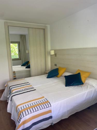 a large white bed with blue and yellow pillows at MBO Michelangelo in Salou