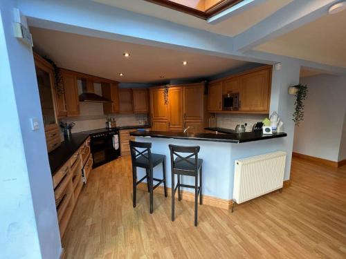 a kitchen with a counter and two stools in it at WATERSIDE 3 BED COTTAGE, HOT TUB, SAUNA, PVT BEACH in Arrochar