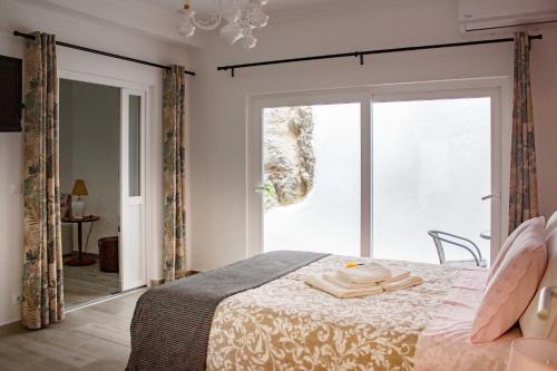 a bedroom with a bed and a large window at Flor&Fidalgo Guest House in Sintra