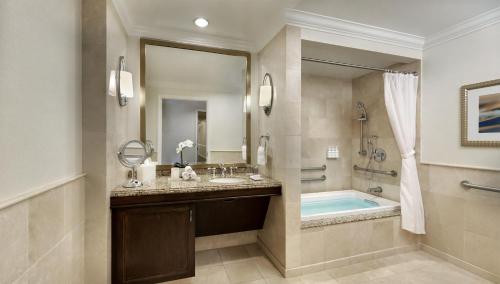 a bathroom with a tub and a sink and a mirror at Balboa Bay Resort in Newport Beach