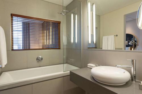 a white bathroom with a sink and a mirror at Radisson Blu Hotel Sandton, Johannesburg in Johannesburg