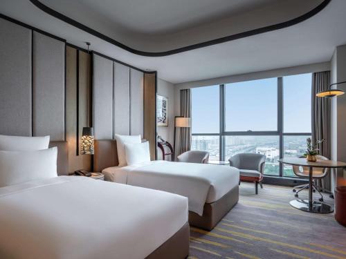 a hotel room with two beds and a table at Pullman Suzhou Zhonghui in Suzhou