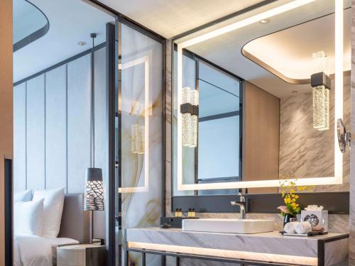 a bathroom with a sink and a large mirror at Pullman Suzhou Zhonghui in Suzhou