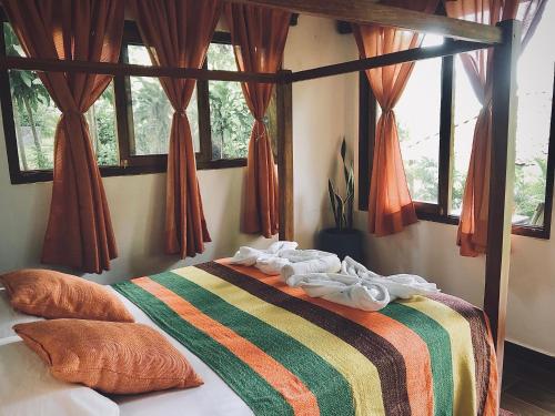 a bedroom with a bed with a striped blanket and windows at Casa Única - Room with breakfast or Cabins with kitchen in La Laguna