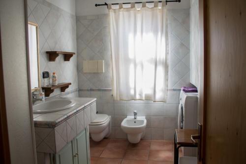 a bathroom with a sink and a toilet and a window at Brezza di Mare in Calasetta