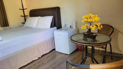 um pequeno quarto com uma mesa com uma cama e uma mesa com flores amarelas em Chalés Poly em São Bento do Sapucaí