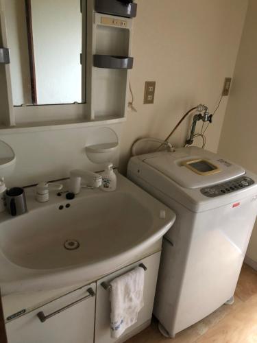 uma casa de banho branca com um lavatório e um espelho em 楠のおうち em Yokkaichi