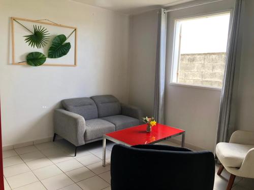sala de estar con sofá y mesa roja en Domaine De Marly, 3 étoiles, en Sainte-Anne