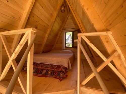 a bedroom in a log cabin with a bed in the attic at A Frame Cottage in Varjanisi - Batumi in K'eda