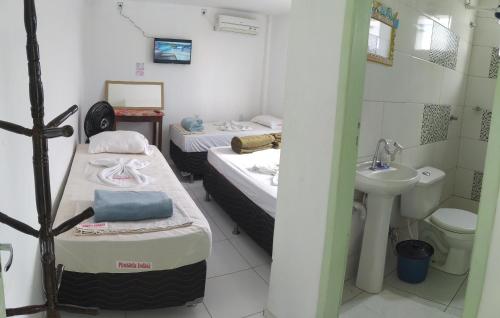 um pequeno quarto com 2 camas e um lavatório em indaiá Pousada - Posto da Mata-BA em Pasto da Mata