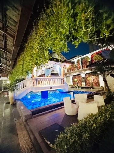 a house with a swimming pool with white furniture at Raintree Boutique Villa & Gallery in Yogyakarta