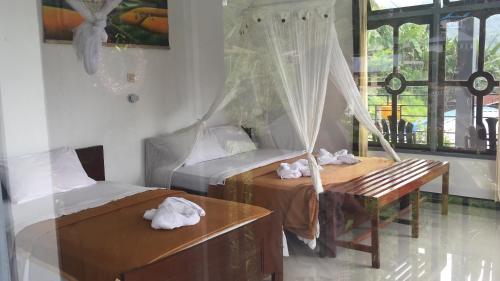 a bedroom with two beds and a bench and a window at Bintang by Tobias Lodge Cafe & Restaurant in Kelimutu