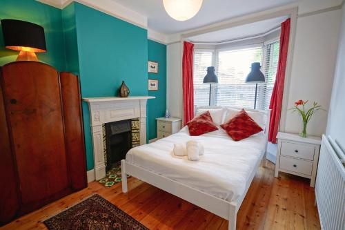 a bedroom with a white bed with red pillows and a fireplace at Boscobel Apartments Down in Winchester