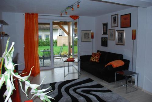 a living room with a black couch and orange curtains at Ferienwohnungen Rexha in Schwangau