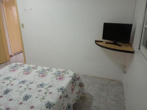 a bedroom with a bed and a television on a shelf at Apartamento com churrasqueira, ótima localização. in Cachoeira do Sul