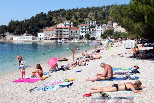 a group of people laying on a beach at Apartments by the sea Drvenik Donja vala, Makarska - 9654 in Drvenik