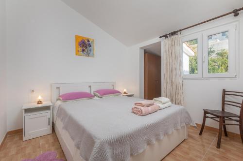 1 dormitorio con 1 cama blanca grande con almohadas rosas en Apartments by the sea Podgora, Makarska - 11469, en Podgora