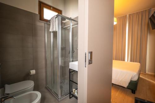 a bathroom with a shower and a toilet and a bed at Albergo Ristorante Il Terziere in Trevi