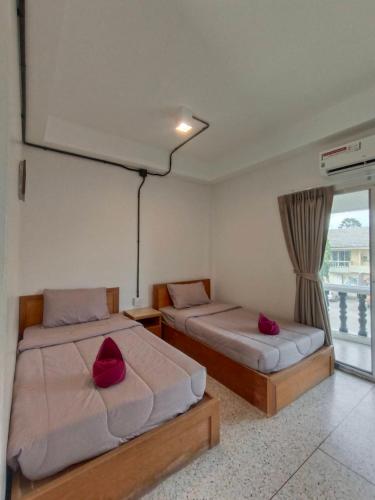 two beds with red pillows in a room with a window at Bangsaphan Resort in Bang Saphan