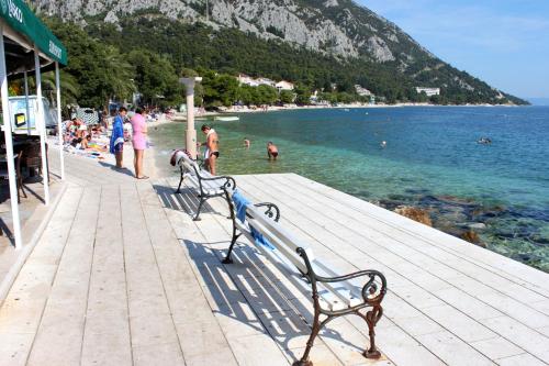 two benches on a pier with people swimming in the water at Double Room Gradac 13179a in Gradac
