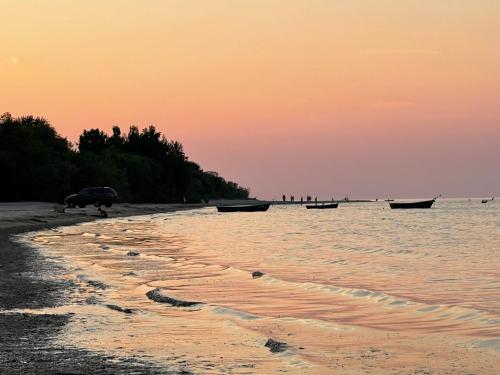 a car parked on a beach with boats in the water at Ragaciema Skadiņi in Ragaciems