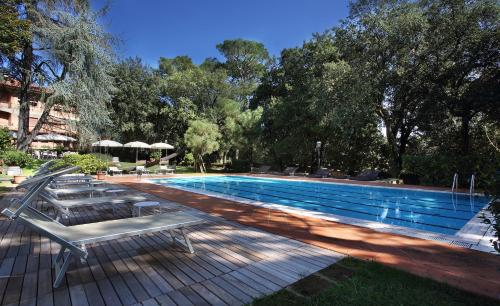 ein Pool mit Bänken und Sonnenschirmen daneben in der Unterkunft Hotel Villa Delle Rose in Pescia