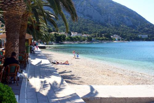 a beach with palm trees and people laying on the beach at Rooms by the sea Gradac, Makarska - 16006 in Gradac