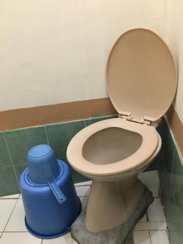 a bathroom with a toilet and a blue trash can at Reynaldo's Upstairs in Puerto Galera