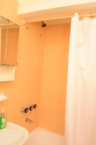 La salle de bains est pourvue d'un rideau de douche blanc et d'un lavabo. dans l'établissement Orillas del Nahuel, à San Carlos de Bariloche