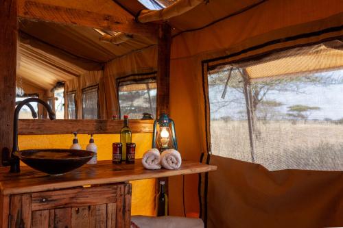 a bathroom with a counter with a sink and a window at Mawe Tented Camp in Serengeti