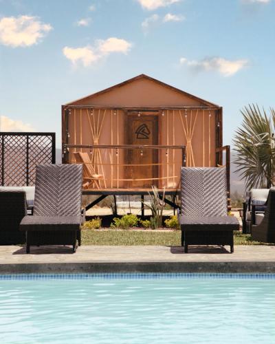 a resort with a pool and two chairs and a house at Indomito Resort & Hotel Boutique in Valle de Guadalupe