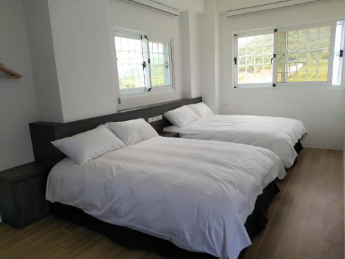 two beds in a room with two windows at Diamond Avenue Homestay in Changbin