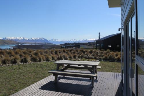a picnic table on a porch with mountains in the background at Ashley Heights in Lake Tekapo